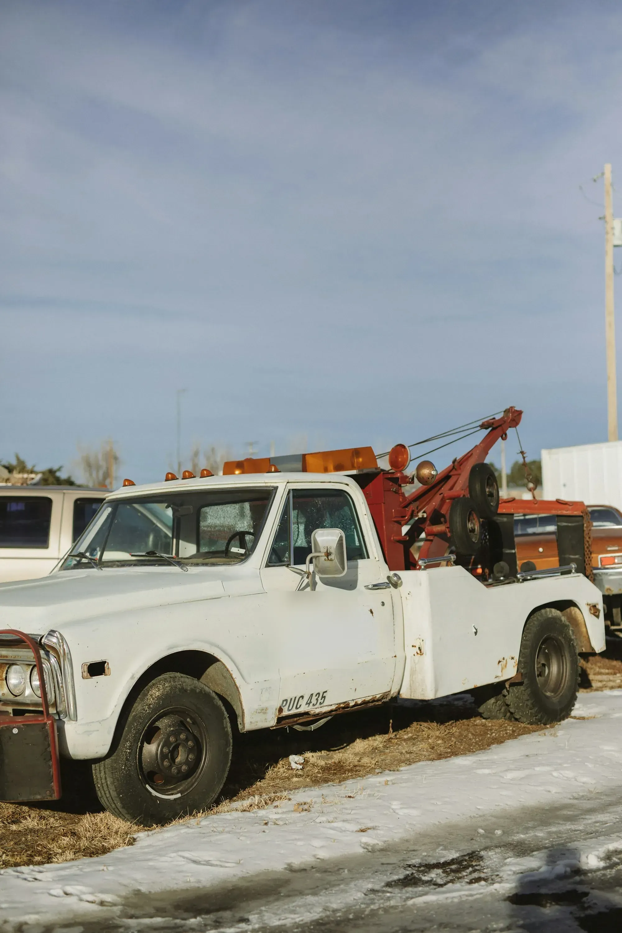 Classic white wrecker tow truck with a red boom parked in a lot