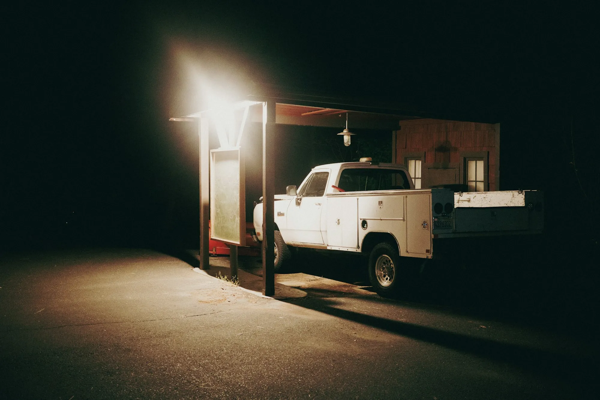 Work truck parked under a single bright light at night