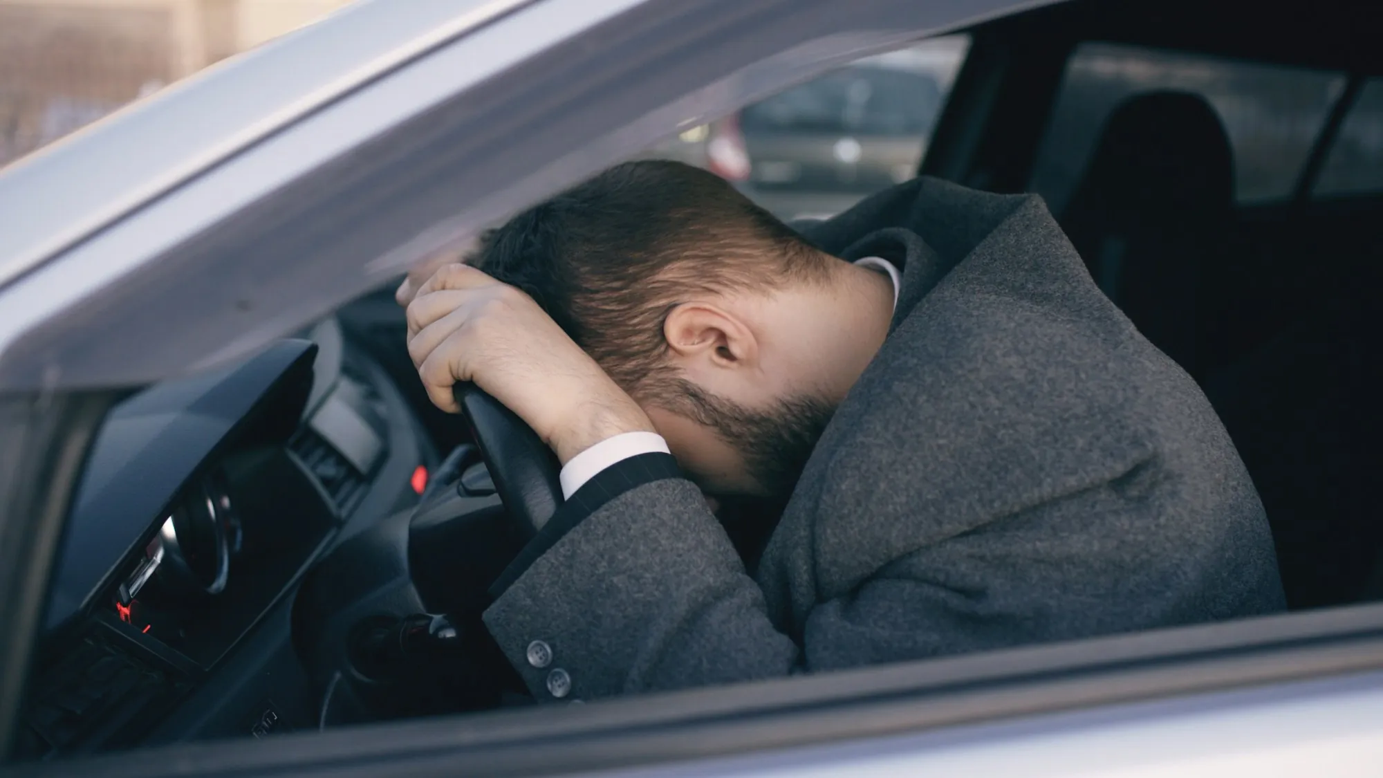 Frustrated driver resting his head on the steering wheel of a stalled car