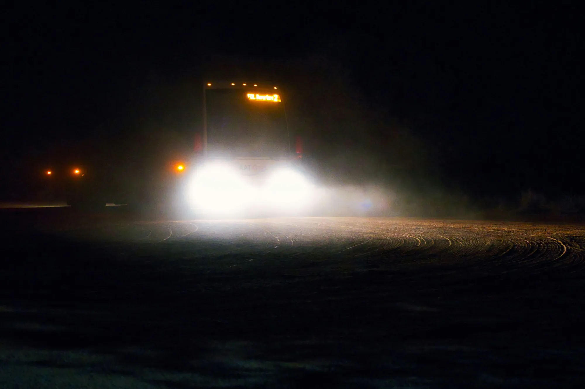 Tow truck headlights cutting through the dark on a rural highway at night