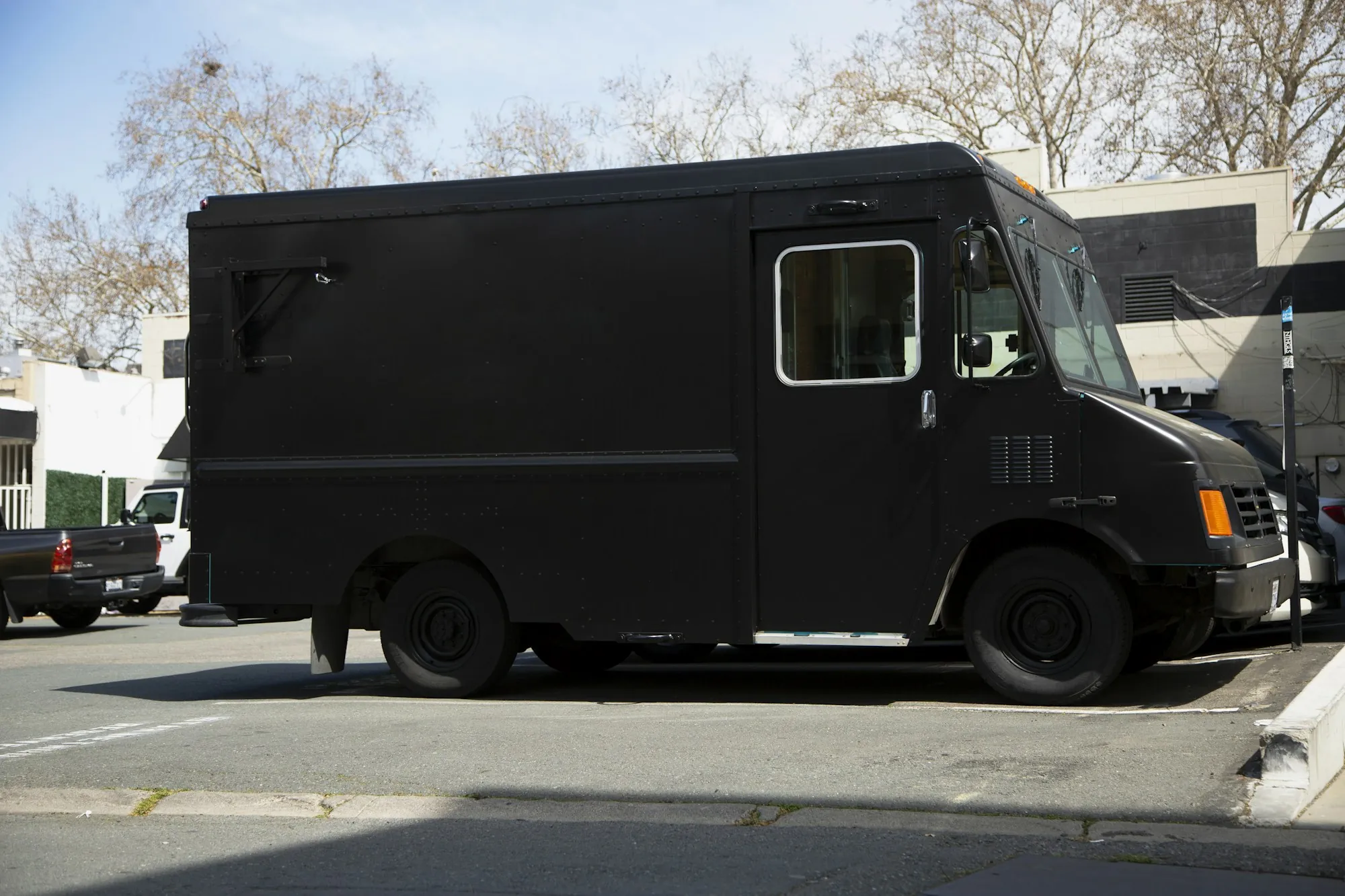 Black step van parked at the curb of a city street