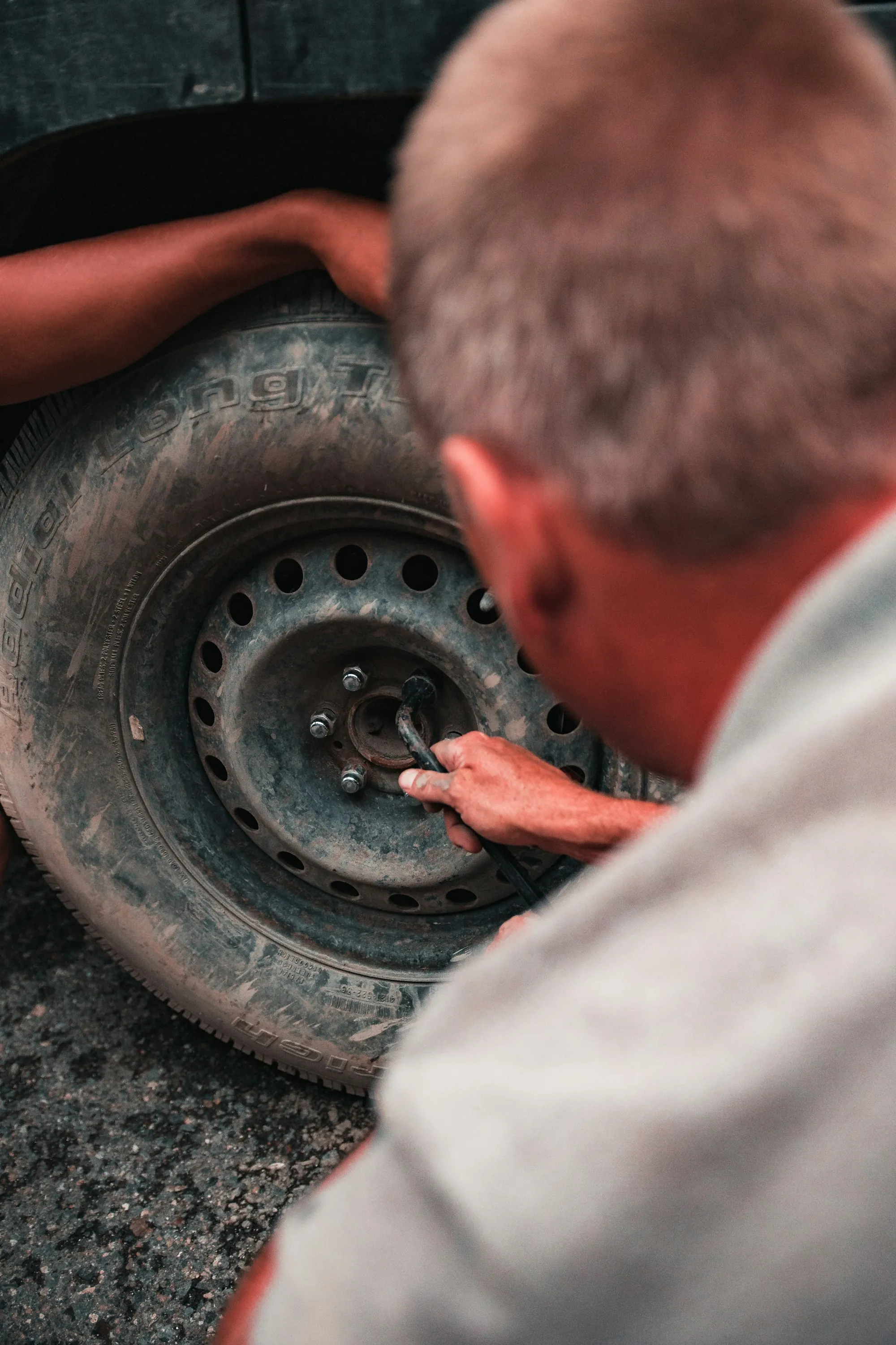 Man loosening lug nuts on a car wheel during a roadside tire change