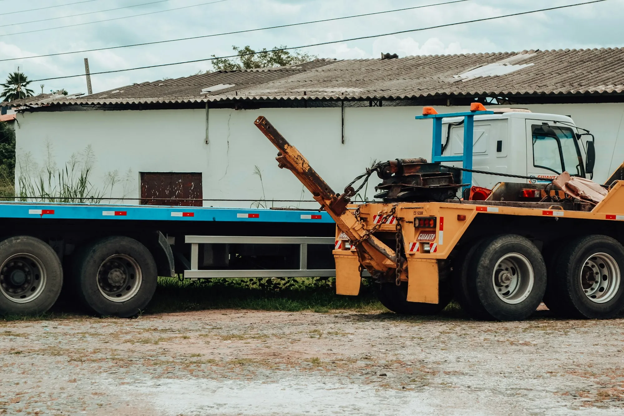 Wrecker tow truck with its boom raised, parked beside a warehouse